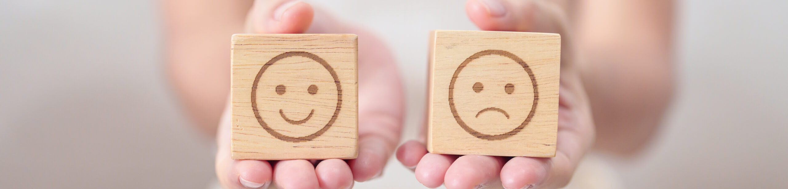 Zwei Holzklötze mit Smileys – Symbol für emotionale Zustände im EFT Basiskurs