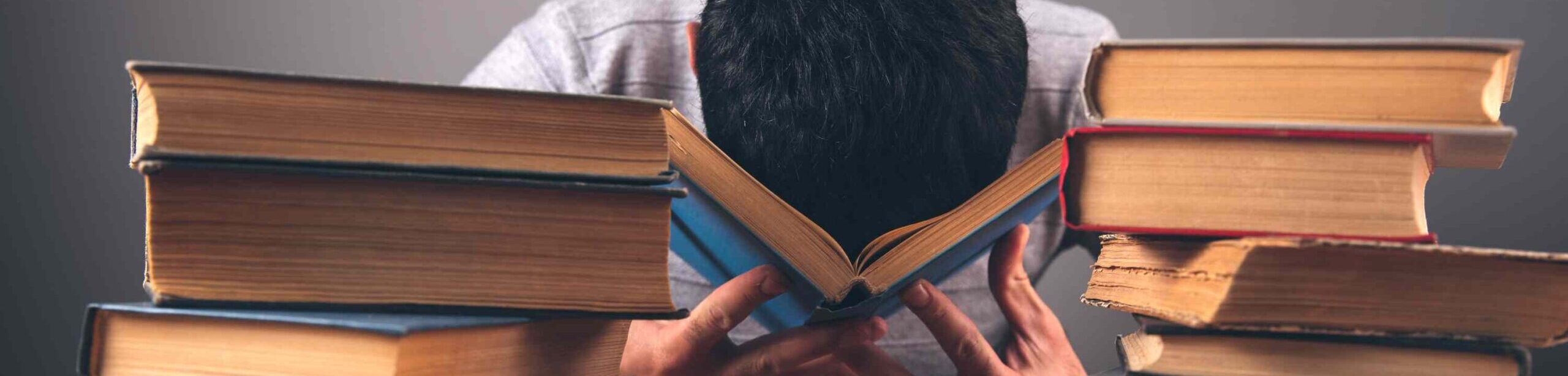 Gestresster Student mit Kopf im Buch – Symbol für Prüfungsangst und Stress