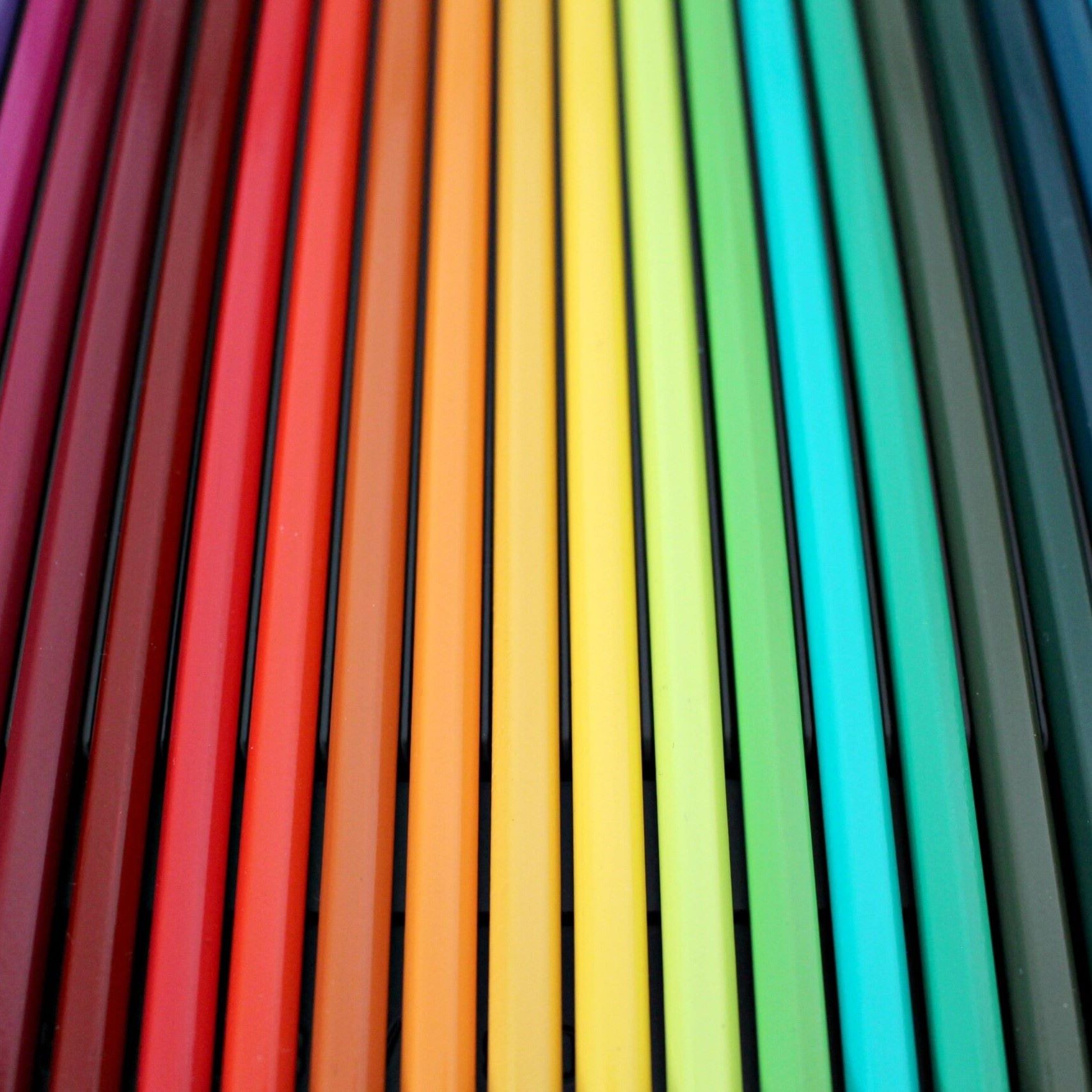 Farbstifte in Regenbogenfarben nebeneinander angeordnet – Symbolbild für Farbtherapie oder kreative Methoden in der Ausbildung.