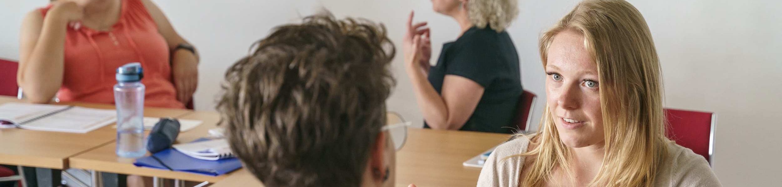 Vier Frauen üben in Zweiergruppen Gesprächsführung und nonverbale Kommunikation im Rahmen des Unterrichts in Psychosoziale Beratung bei APAMED.