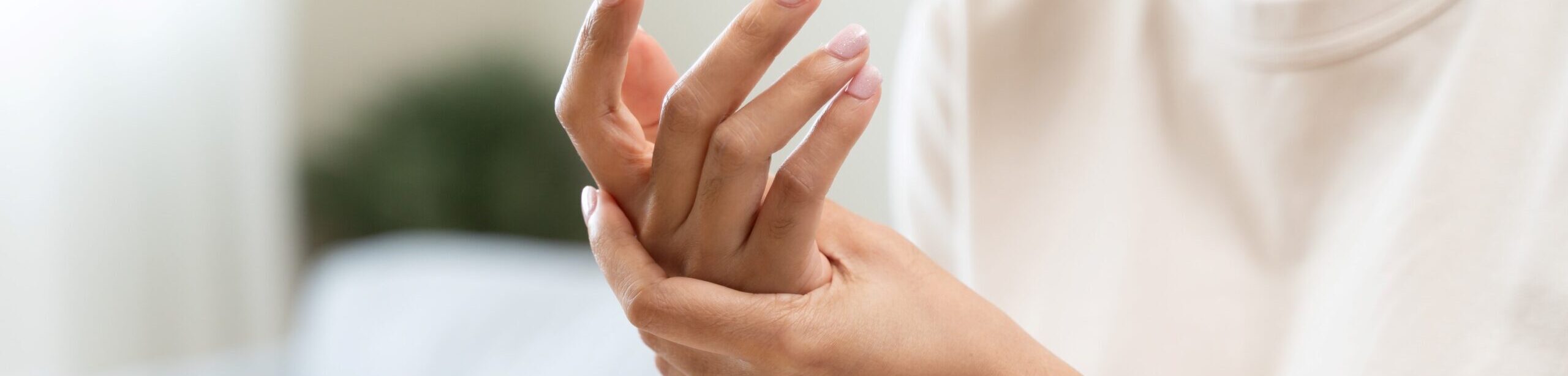 Frau hält schmerzende Hand – typisches Symptom bei rheumatischen Erkrankungen