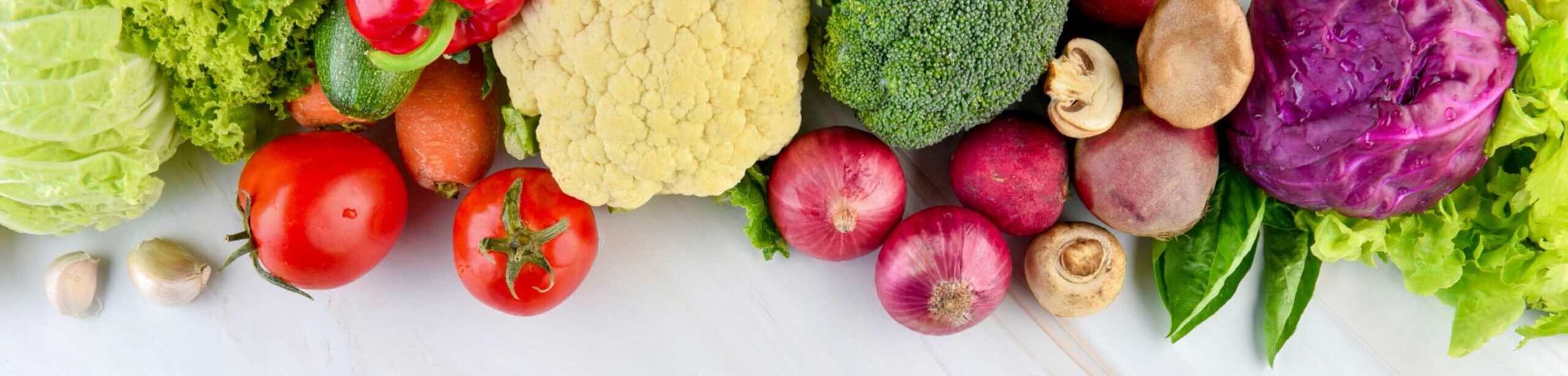 Frisches Gemüse wie Brokkoli, Kohl, Tomaten und Zwiebeln auf hellem Hintergrund, gesund und kalziumreich