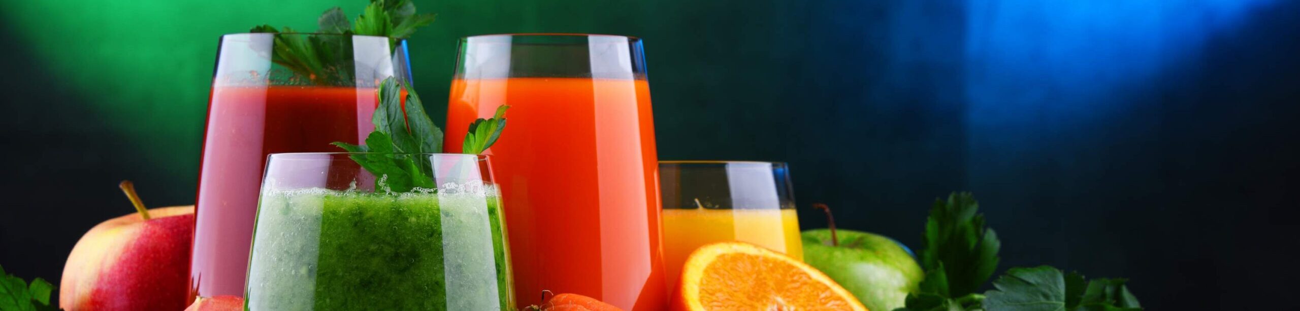 Frische Obst- und Gemüsesäfte mit Zutaten wie Karotten, Gurken, Orangen und Äpfeln – Symbol für basische Ernährung