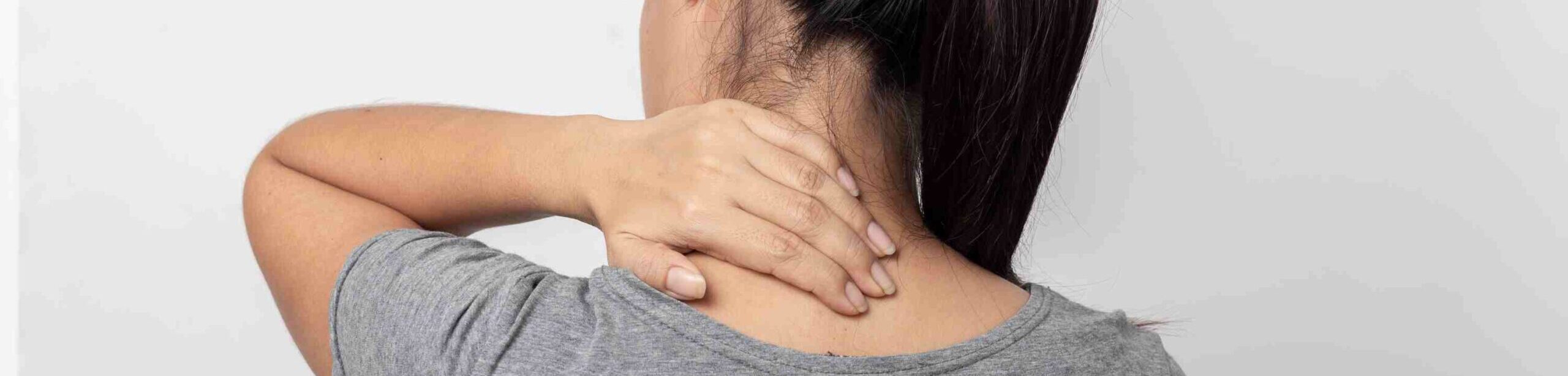 Frau greift sich an den verspannten Nacken – Symbolbild für chronische Schmerzen