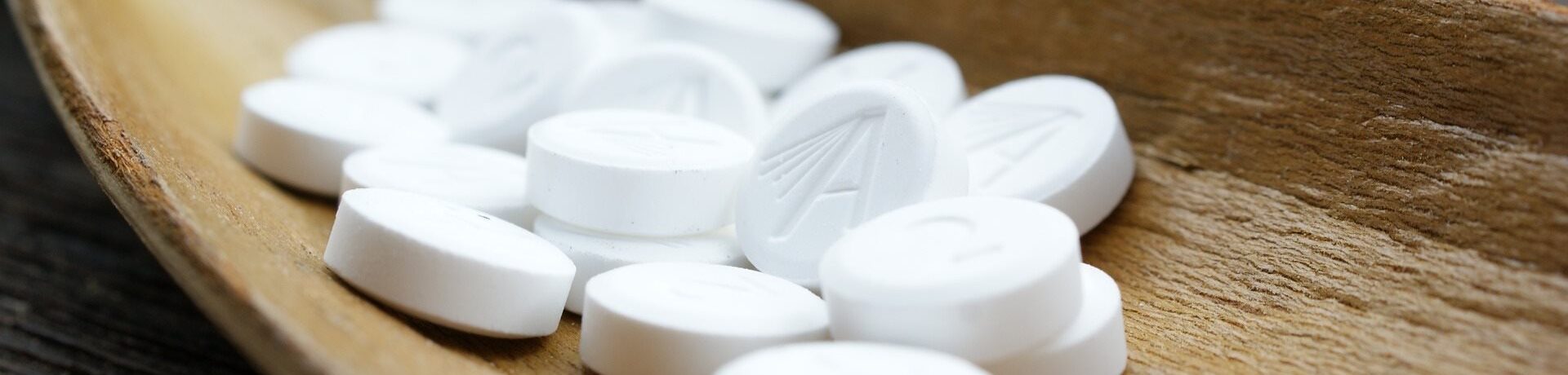 Weiße Schüssler-Salze Tabletten in einer Holzschale – natürliche Mineralstofftherapie
