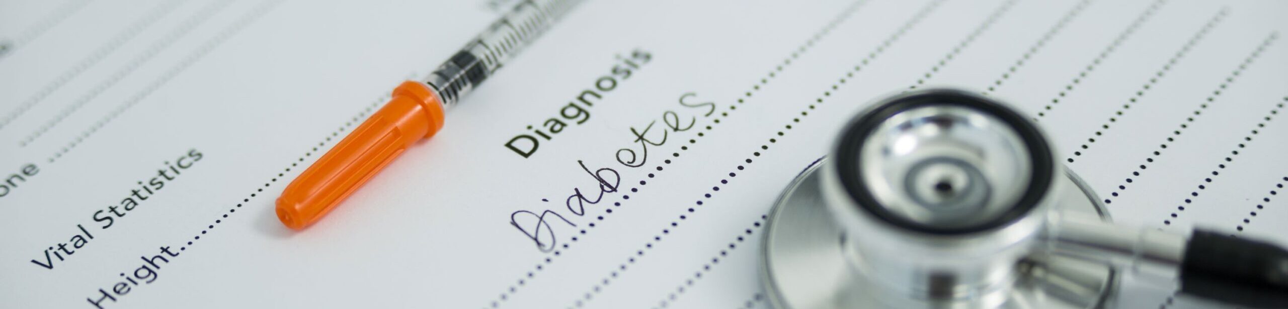 Diagnoseformular mit „Diabetes“, Insulinspritze und Stethoskop – Symbolbild für Diabetesbehandlung