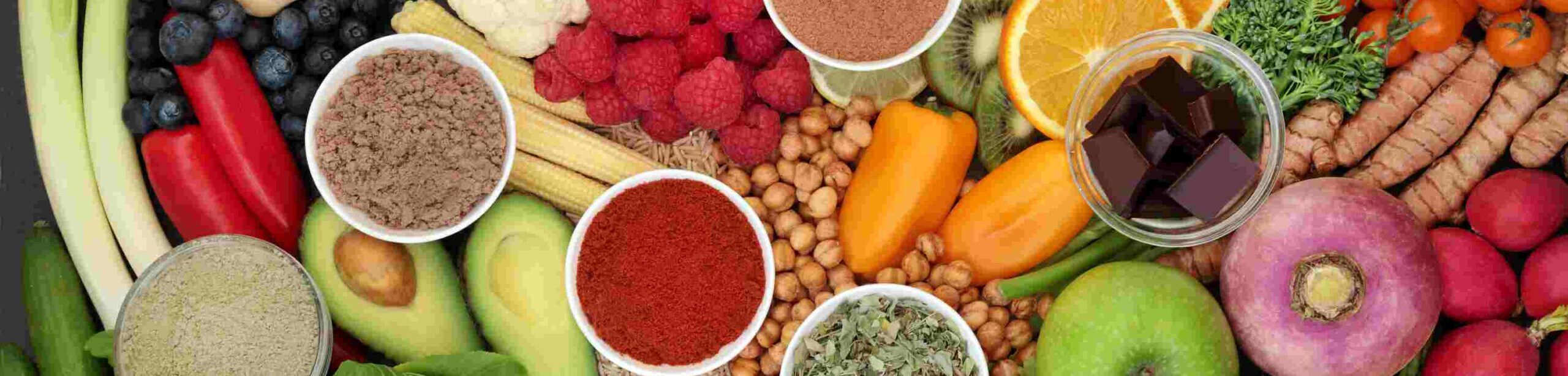 Bunte Auswahl an frischem Obst, Gemüse, Vollkornprodukten und Gewürzen als Symbol für eine ausgewogene Vollwertkost