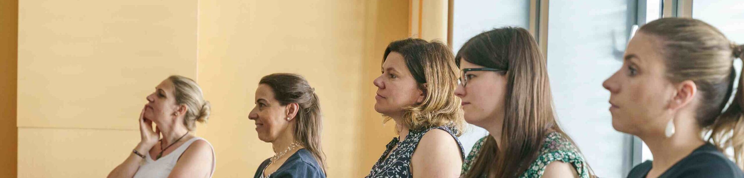 Seminare KomplementärTherapie: Fünf Frauen sitzen in einem APAMED-Seminarraum und verfolgen konzentriert den Unterricht mit Unterlagen und Notizen.