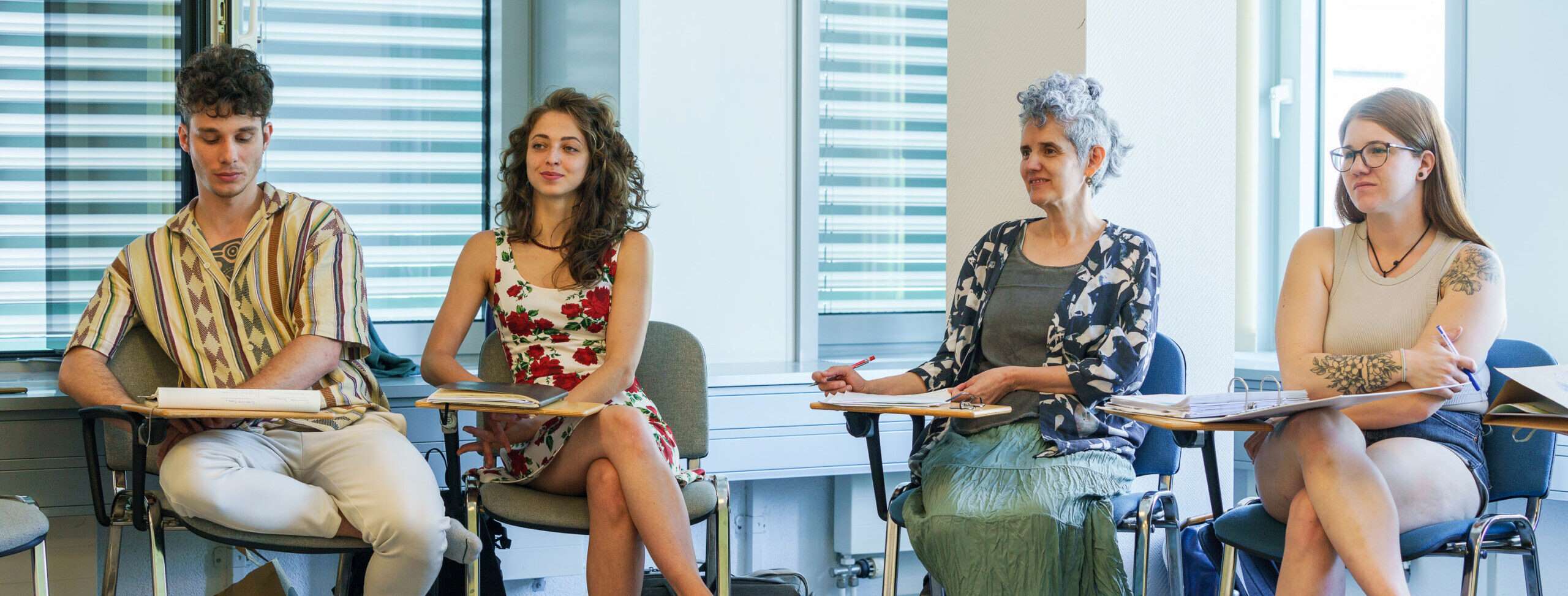 Vier Personen sitzen in einem Seminarraum im Stuhlkreis und nehmen an einer Unterrichtseinheit teil.