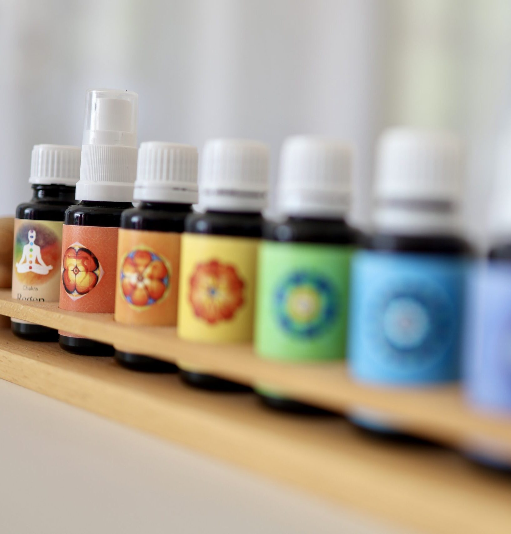 Farbtherapie Ausbildung: Kleine Glasfläschchen mit bunten Etiketten in den Farben des Regenbogens – Symbol für Chakrenarbeit, energetische Balance und ganzheitliche Farbheilung.